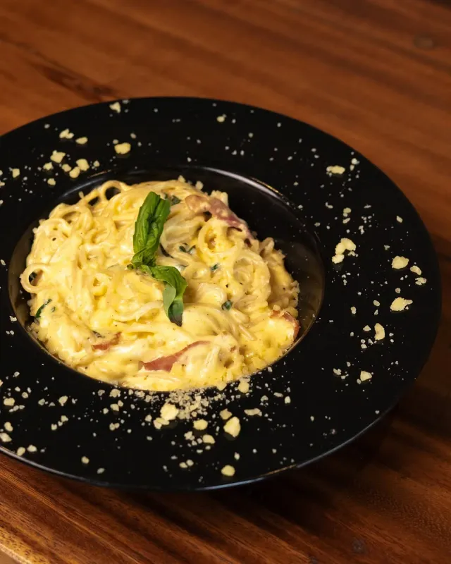 Creamy carbonara dalam piring hitam.